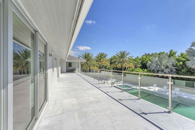 balcony featuring a pool with connected hot tub