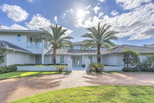 view of front facade featuring a tile roof, french doors, and stucco siding
