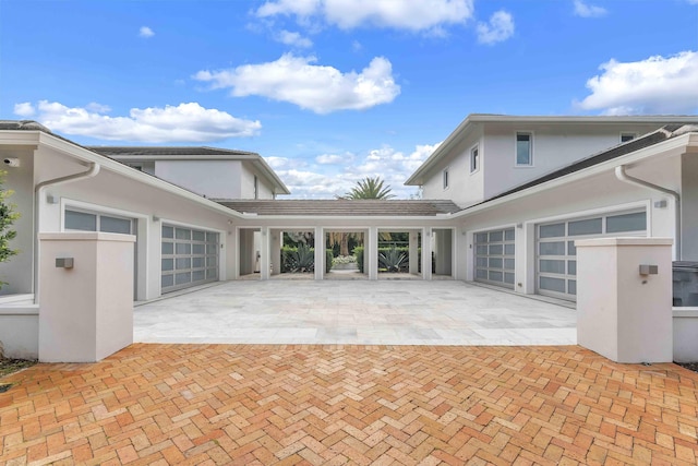 view of front of property featuring a garage, stucco siding, and decorative driveway