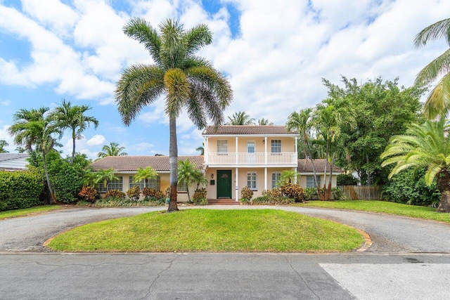255 Russlyn Dr, West Palm Beach, FL 33405 - view of front of home featuring a tiled roof, a balcony, curved driveway, stucco siding, and a front yard