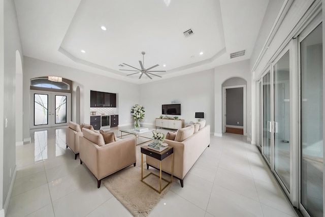living room featuring arched walkways, visible vents, french doors, and a tray ceiling