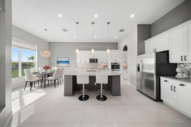 kitchen with a kitchen breakfast bar, a sink, backsplash, and stainless steel appliances