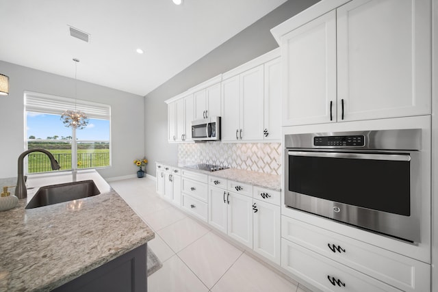 kitchen featuring a sink, visible vents, stainless steel appliances, baseboards, and backsplash