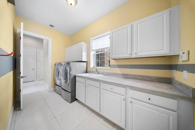 washroom with a sink, cabinet space, light tile patterned floors, separate washer and dryer, and visible vents