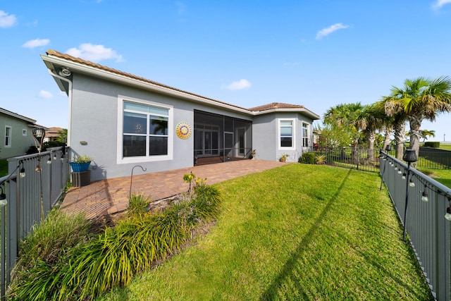 back of property featuring stucco siding, a fenced backyard, a yard, and a sunroom