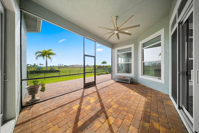 unfurnished sunroom featuring ceiling fan