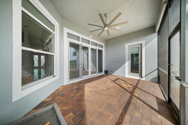 unfurnished sunroom featuring ceiling fan