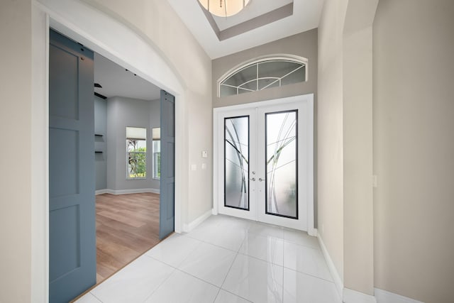 entrance foyer with baseboards, light tile patterned floors, and french doors