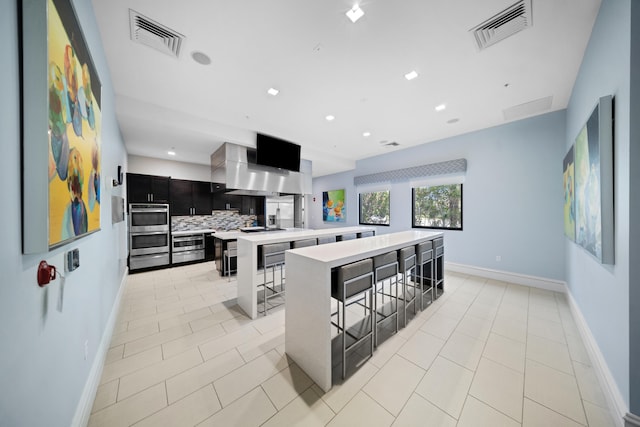 kitchen featuring a kitchen breakfast bar, stainless steel double oven, visible vents, and a spacious island
