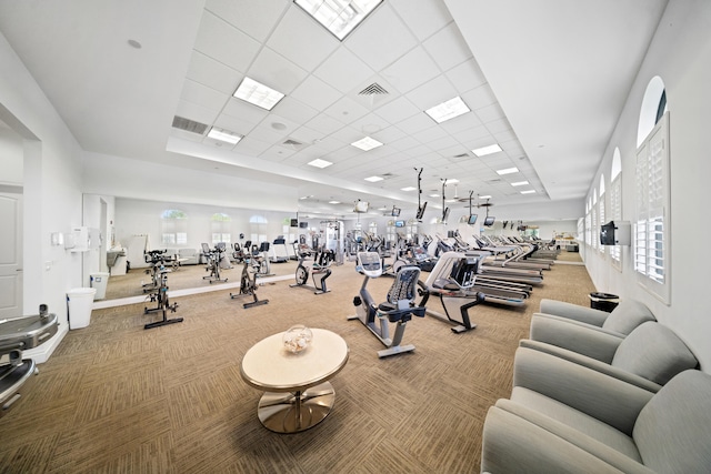 gym with a healthy amount of sunlight, carpet flooring, and a drop ceiling