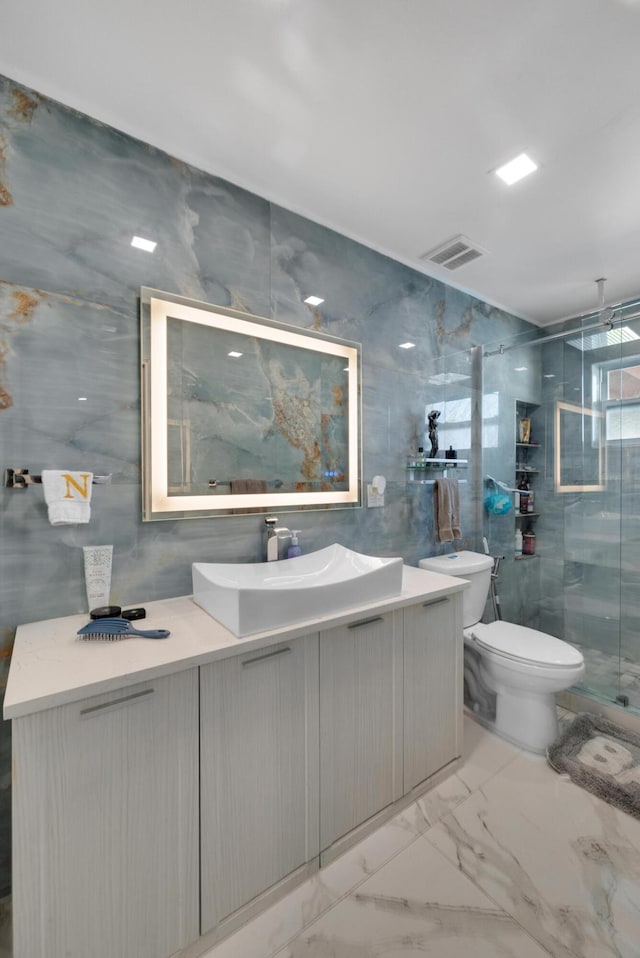 bathroom featuring toilet, tile walls, a stall shower, marble finish floor, and vanity