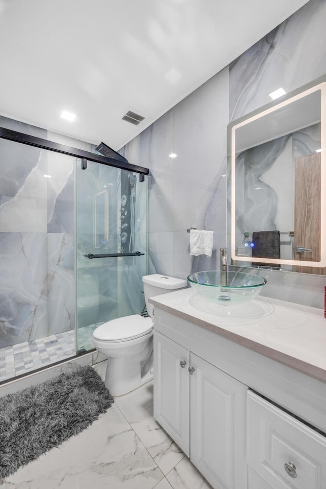 bathroom with a marble finish shower, tile walls, visible vents, marble finish floor, and vanity