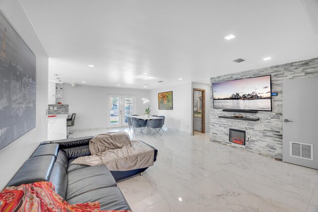 living room with a stone fireplace, visible vents, and recessed lighting