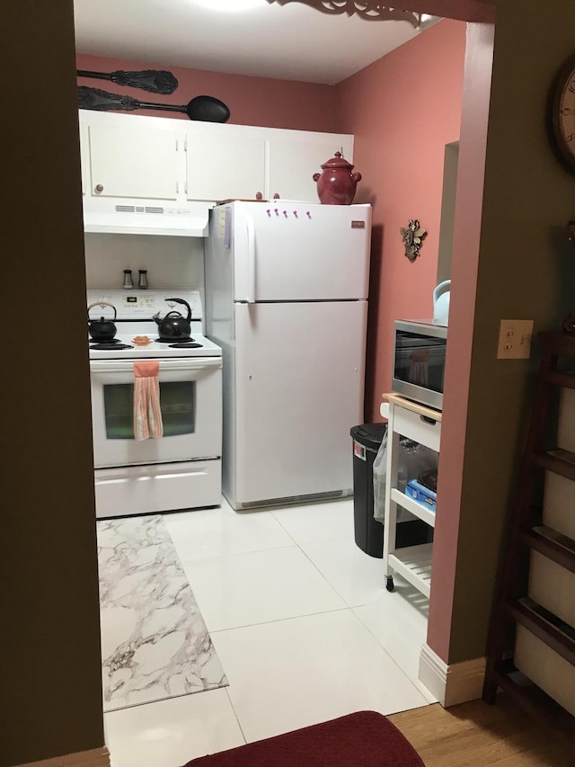kitchen with white appliances, under cabinet range hood, and white cabinets