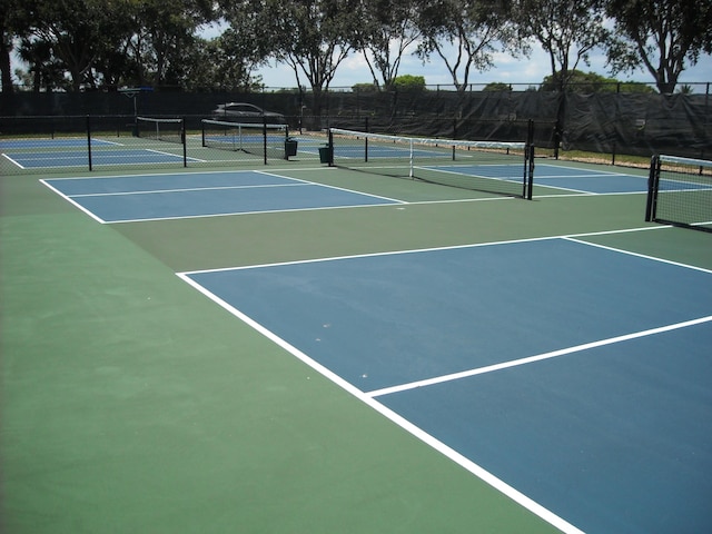 view of tennis court with community basketball court and fence