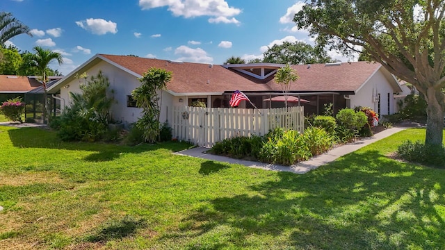 view of property exterior featuring roof with shingles, stucco siding, a yard, and fence