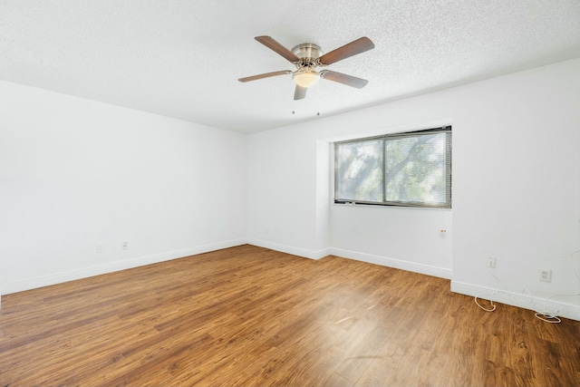 empty room featuring baseboards, wood finished floors, a textured ceiling, and ceiling fan