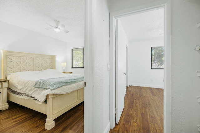 bedroom featuring baseboards, a textured ceiling, and dark wood-type flooring