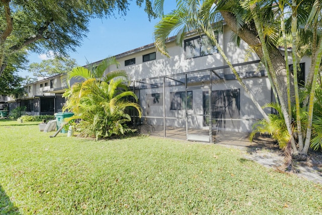 rear view of house with a patio area, a lanai, a yard, and stucco siding