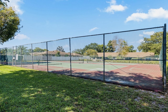 view of sport court with a lawn and fence
