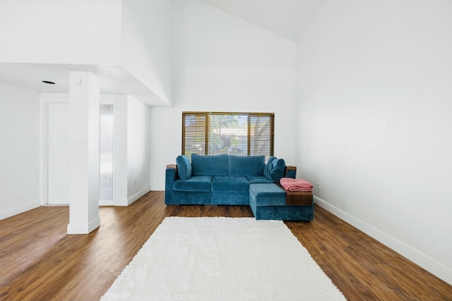 living area featuring high vaulted ceiling, baseboards, and dark wood-style floors