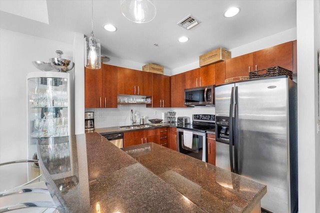 300 S Australian Ave Unit 717, West Palm Beach, FL 33401 - kitchen featuring appliances with stainless steel finishes, brown cabinetry, pendant lighting, recessed lighting, and decorative backsplash