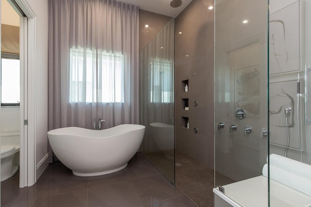 bathroom featuring tile patterned flooring, a soaking tub, toilet, and a stall shower