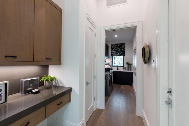 hall with dark wood finished floors, washing machine and dryer, baseboards, and visible vents