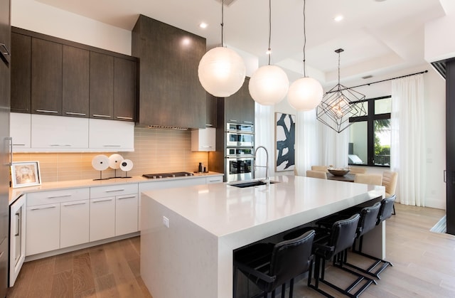 kitchen featuring light countertops, a raised ceiling, modern cabinets, and a sink