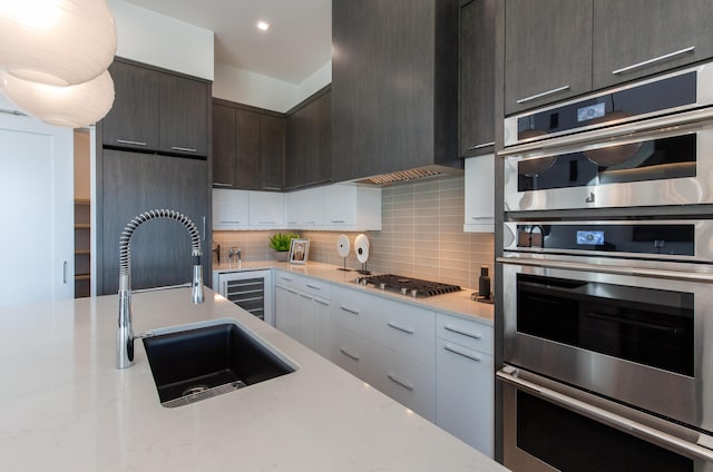 kitchen with a sink, decorative backsplash, modern cabinets, dark brown cabinetry, and appliances with stainless steel finishes