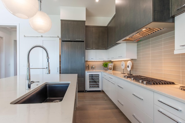 kitchen with stainless steel gas stovetop, light countertops, a sink, and wine cooler