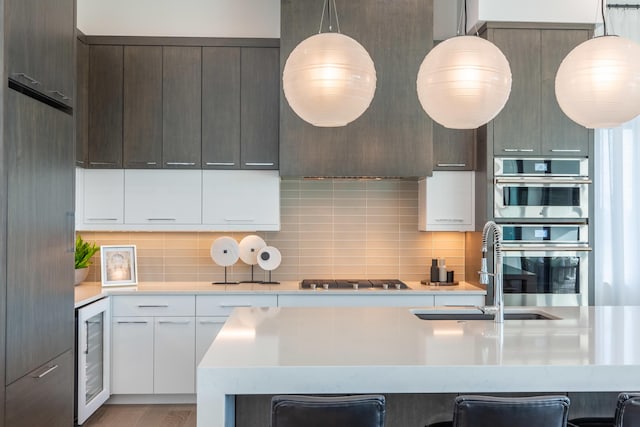 kitchen featuring appliances with stainless steel finishes, beverage cooler, a sink, and light countertops