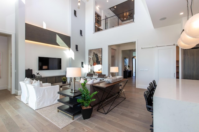 living area featuring baseboards, a towering ceiling, and light wood-style floors