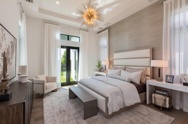 bedroom featuring wallpapered walls, wood finished floors, access to exterior, an accent wall, and a notable chandelier