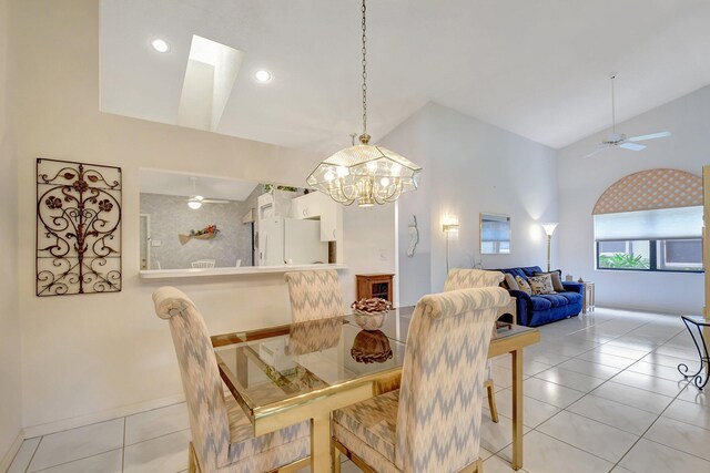dining space with baseboards, high vaulted ceiling, light tile patterned floors, and ceiling fan with notable chandelier