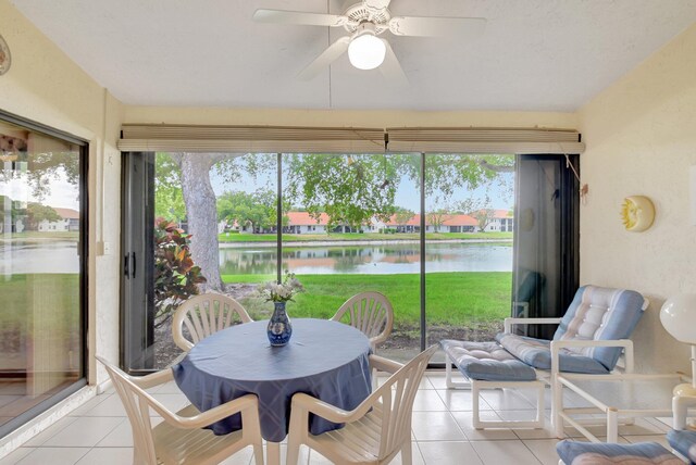 sunroom / solarium featuring a ceiling fan, tile patterned flooring, and a water view