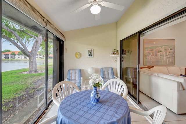 sunroom featuring tile patterned floors, ceiling fan, outdoor dining space, and a water view