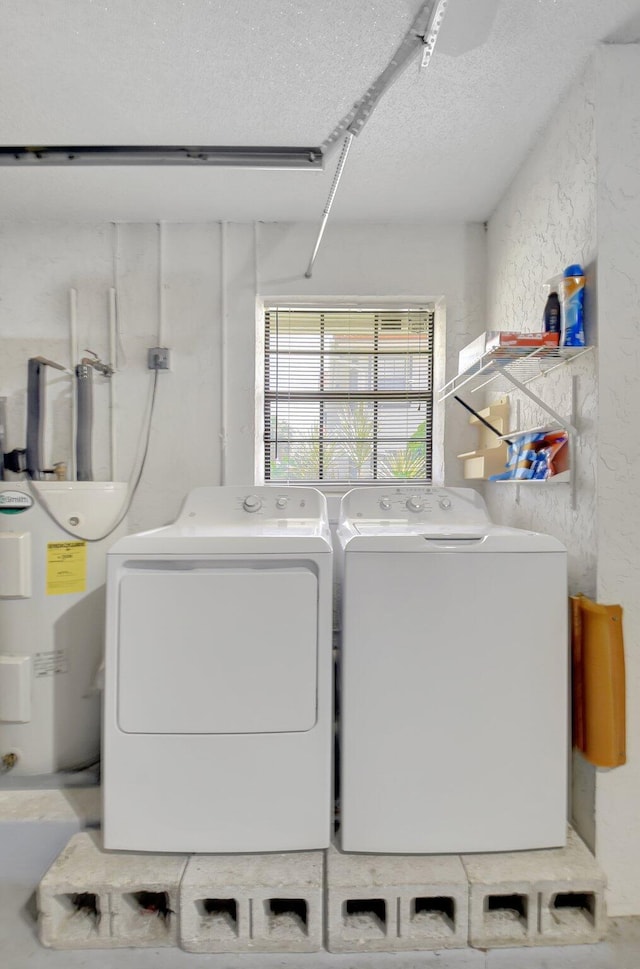 washroom with washer and clothes dryer, a textured ceiling, laundry area, and electric water heater