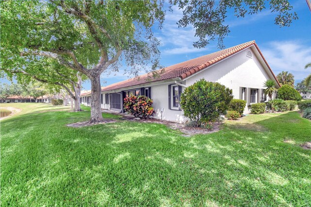 view of home's exterior featuring stucco siding, a yard, and a tiled roof