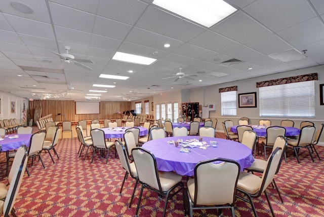 carpeted dining space with ceiling fan, a paneled ceiling, and visible vents