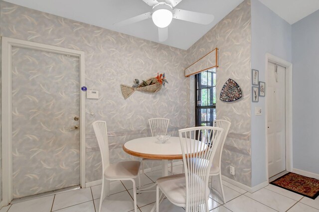 tiled dining area featuring a ceiling fan and wallpapered walls