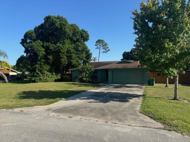 single story home with an attached garage, a front lawn, and concrete driveway