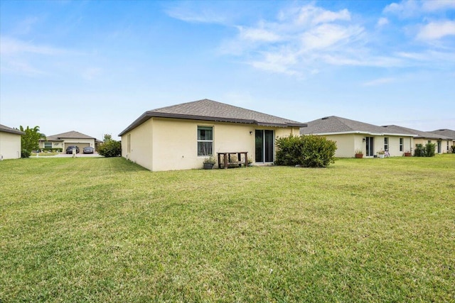 rear view of house featuring a lawn and stucco siding