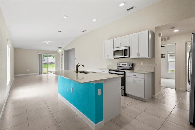 kitchen featuring stainless steel appliances, a sink, lofted ceiling, a center island with sink, and light tile patterned floors