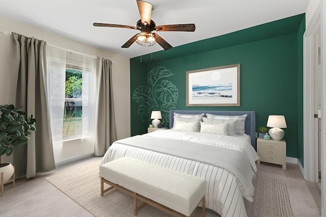 bedroom featuring light carpet, an accent wall, and a ceiling fan
