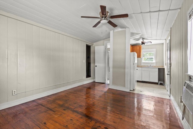 unfurnished living room with light wood finished floors, vaulted ceiling, a ceiling fan, a sink, and baseboards