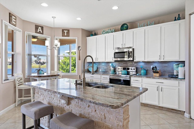 1018 NW Demedici Rd, Port Saint Lucie, FL 34986 - kitchen with appliances with stainless steel finishes, a sink, a center island with sink, tasteful backsplash, and white cabinetry
