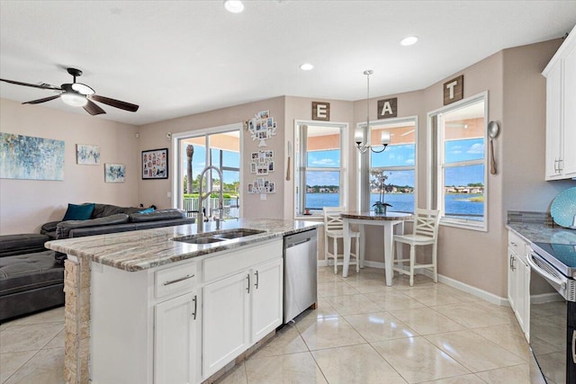1018 NW Demedici Rd, Port Saint Lucie, FL 34986 - kitchen featuring a sink, stainless steel appliances, light stone counters, open floor plan, and white cabinets