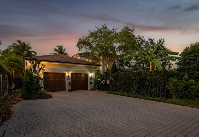 2409 NE 12th St, Fort Lauderdale, FL 33304 - view of front of home with a tile roof, decorative driveway, an attached garage, fence, and stucco siding