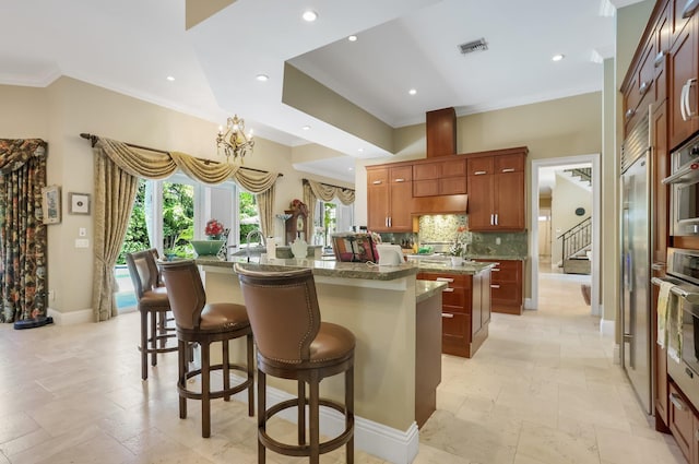 2409 NE 12th St, Fort Lauderdale, FL 33304 - kitchen featuring visible vents, stone tile flooring, crown molding, a kitchen island with sink, and stainless steel oven